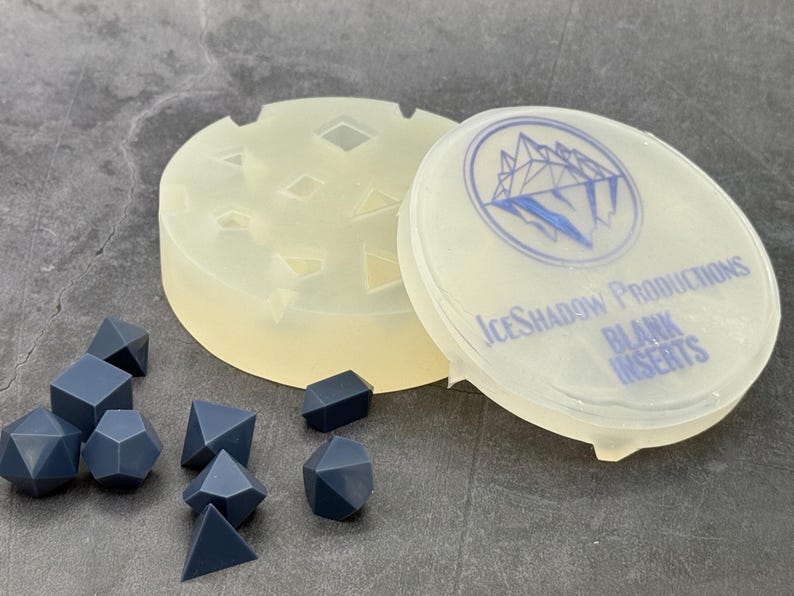 Blank insert silicone dice mold and matching lid beside unnumbered gray dice masters