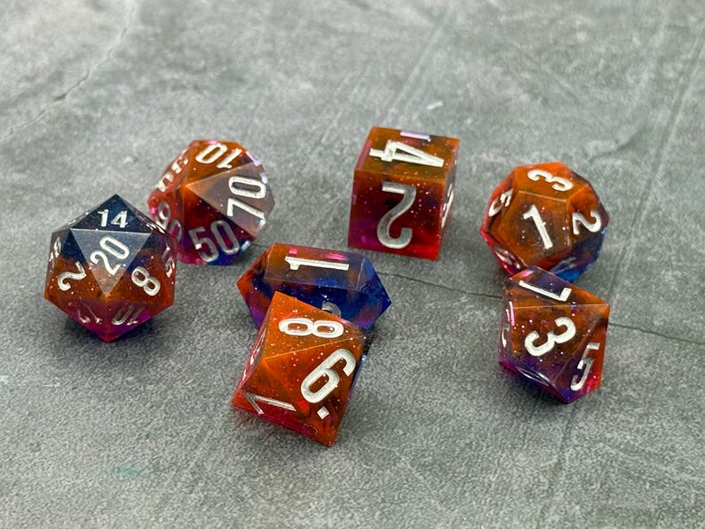 Nebulae handmade resin dice with orange, purple, and blue layers and silver numbers