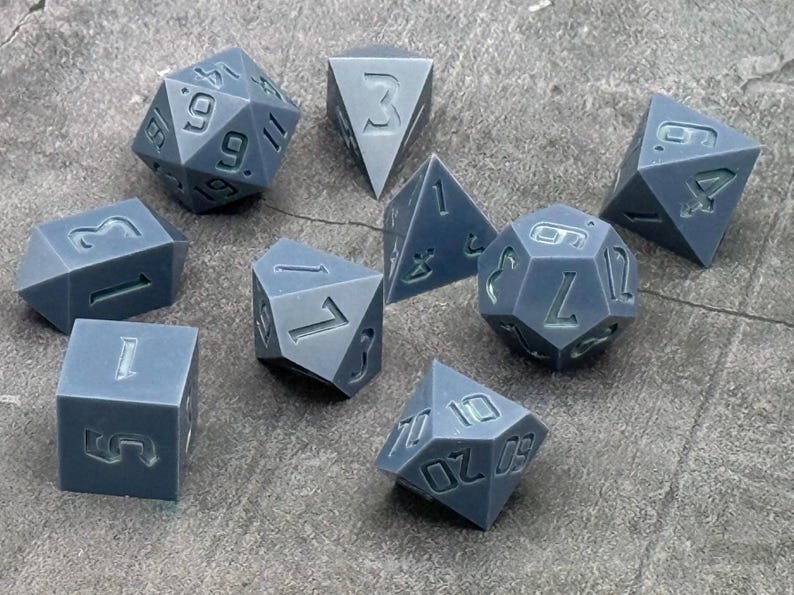 Polished gray polyhedral dice masters with recessed numbers and three D4 shapes